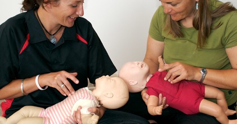 Two women administering first aid to dummy babies